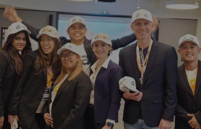 Team of professionals at a business event in Australia, wearing branded d&a hats and showcasing collaboration and diversity.