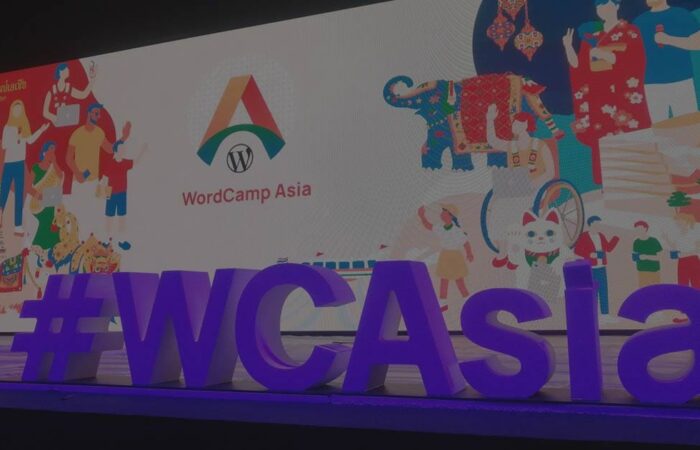 WordCamp Asia stage with a colorful backdrop featuring cultural elements with a large '#WCAsia' signage in the foreground.